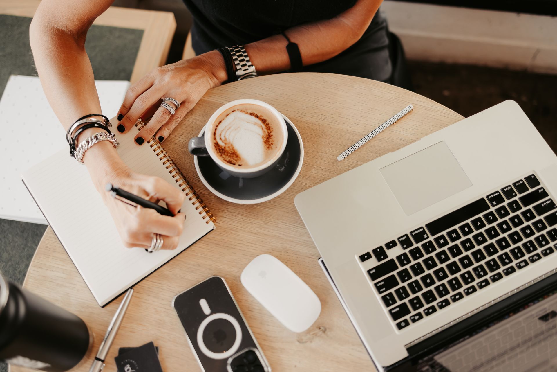 A woman is sitting at a table with a cup of coffee and a laptop.