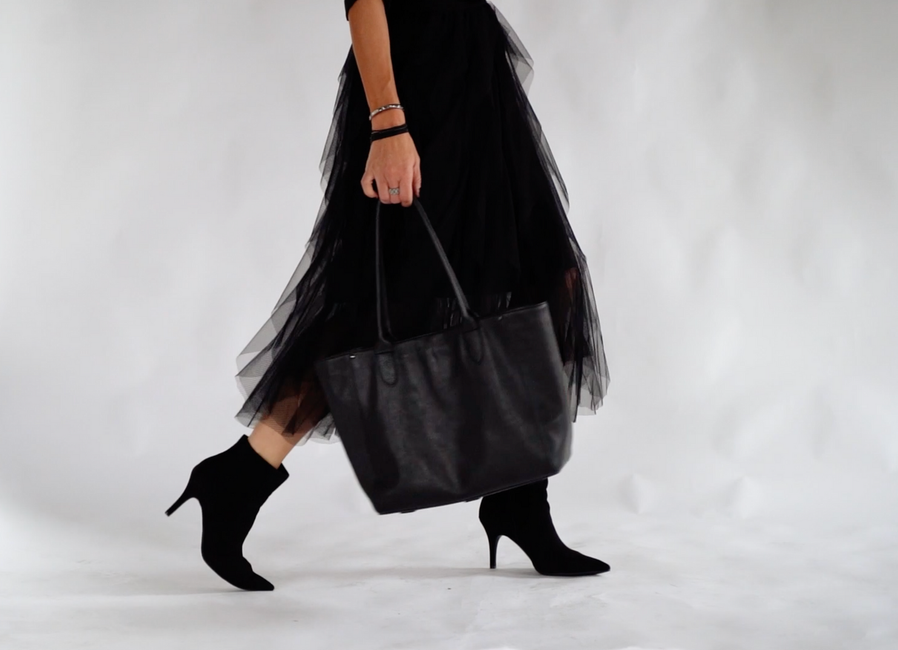 A woman in a black skirt is carrying a black bag.