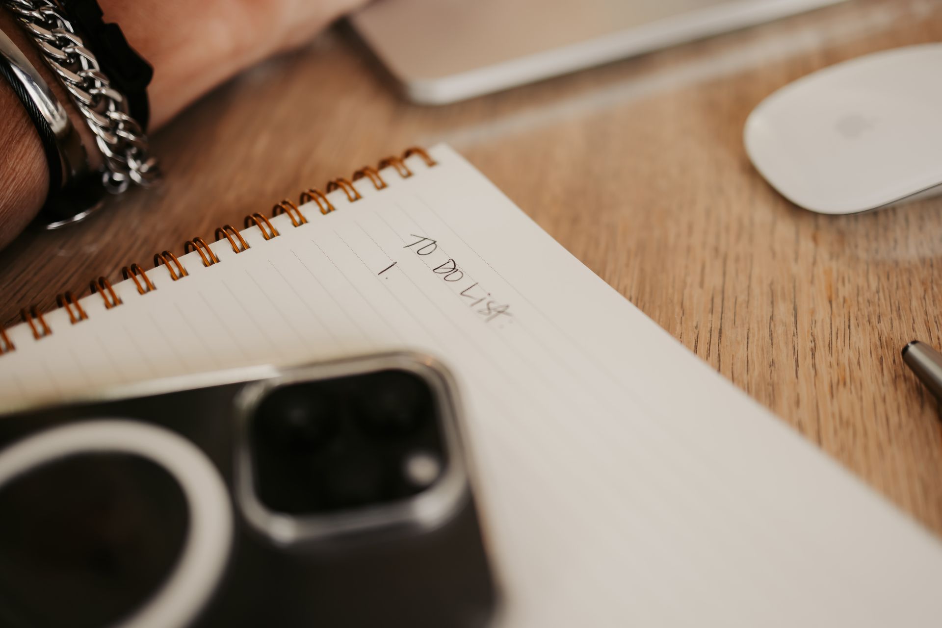 A person is writing in a notebook on a wooden table.