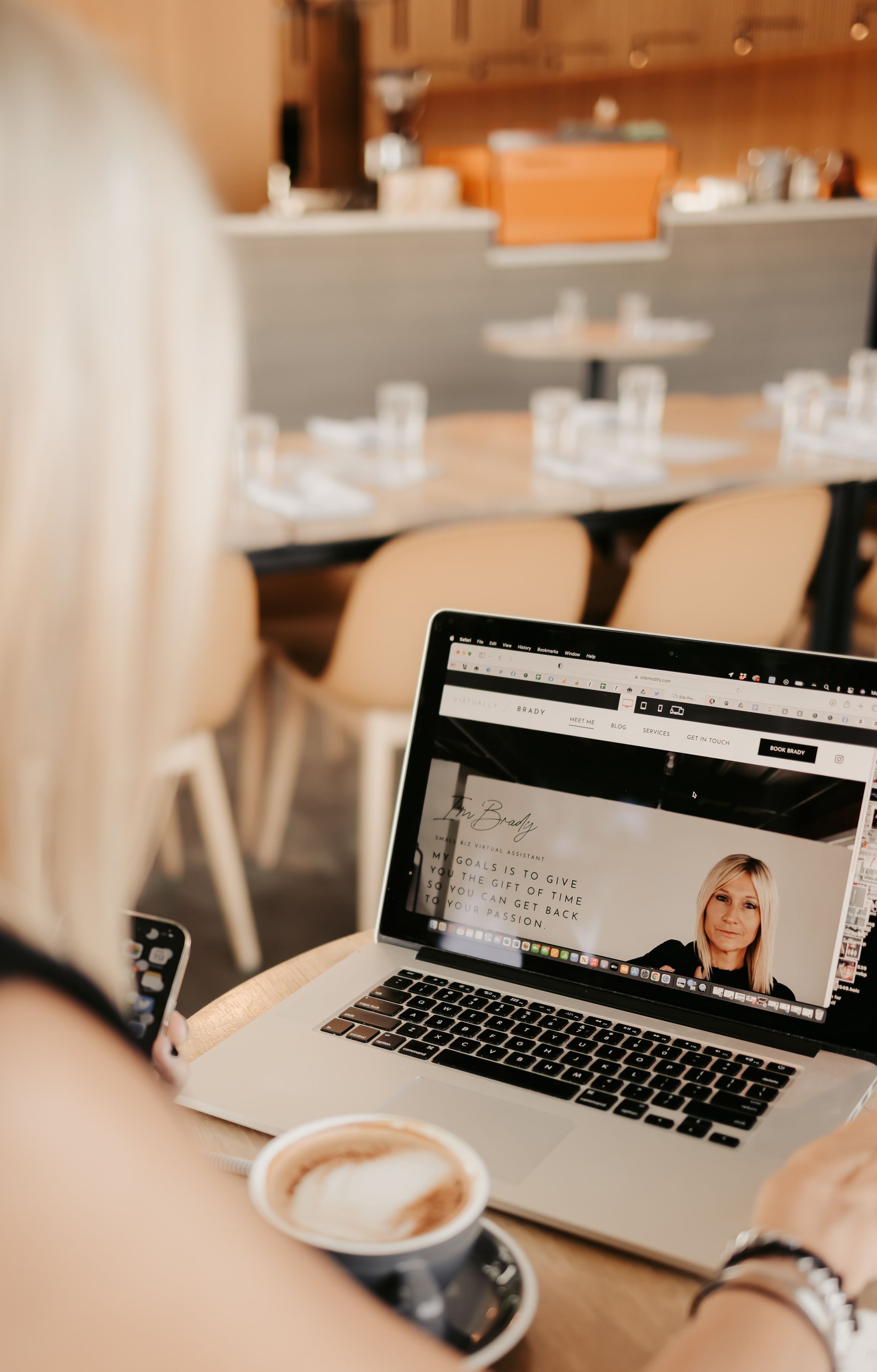 A woman is sitting at a table with a laptop and a cup of coffee.