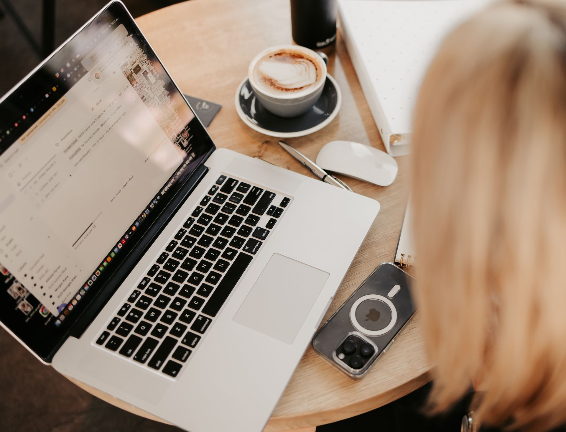 A woman is sitting at a table with a laptop and a cup of coffee.