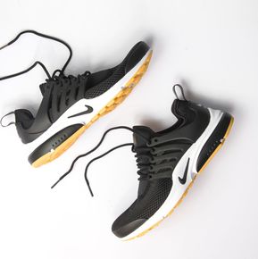 A pair of black and yellow nike sneakers on a white surface