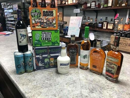 A variety of alcoholic beverages are sitting on a counter in a liquor store.