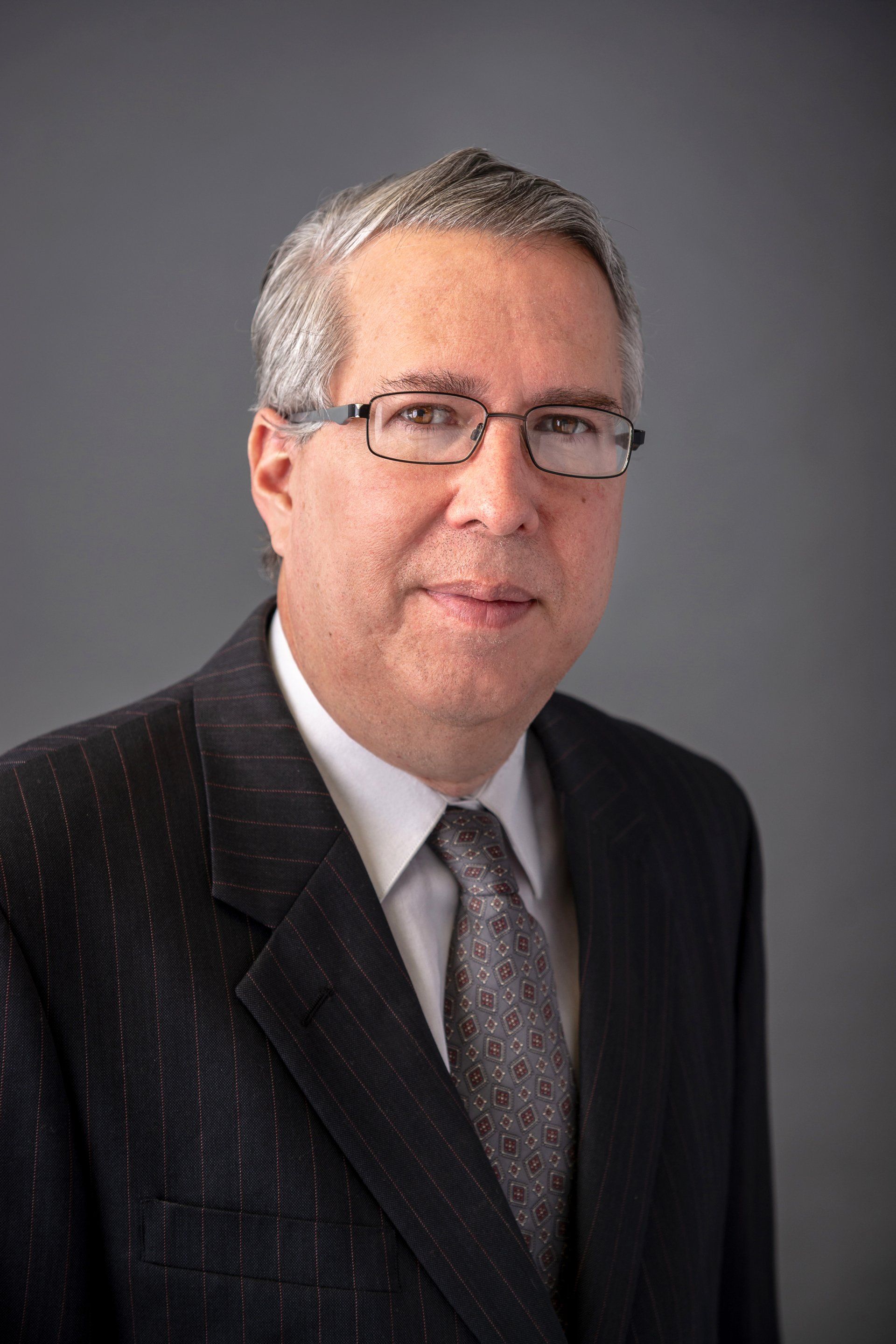A man in a suit and tie is wearing glasses.