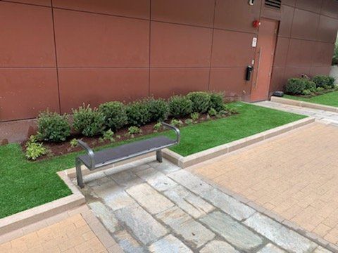 A bench is sitting on a sidewalk in front of a building.