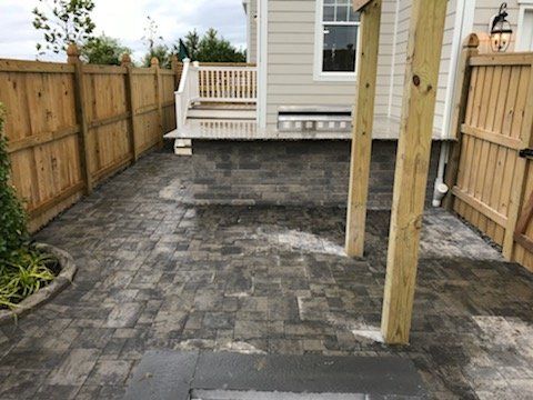A patio with a wooden fence in front of a house.