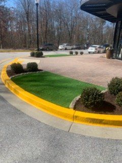 A parking lot with a yellow curb and a green lawn.