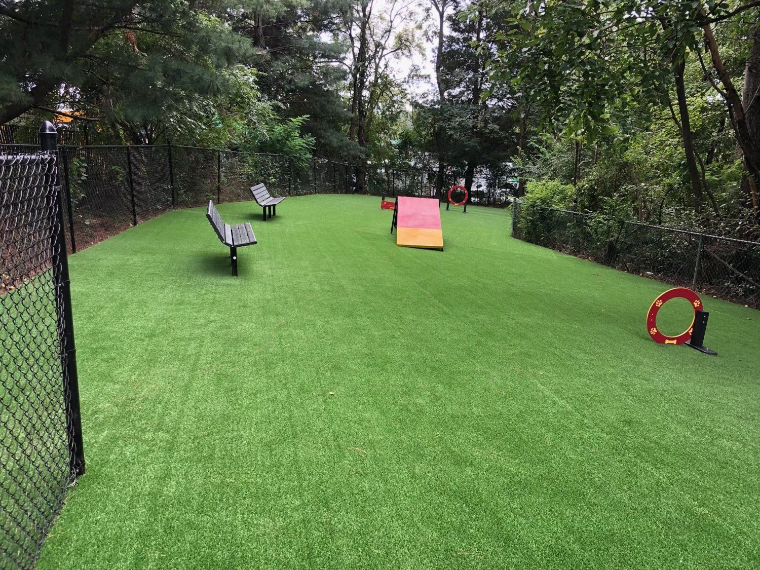 A dog park with a fence and a bench in the middle of it.