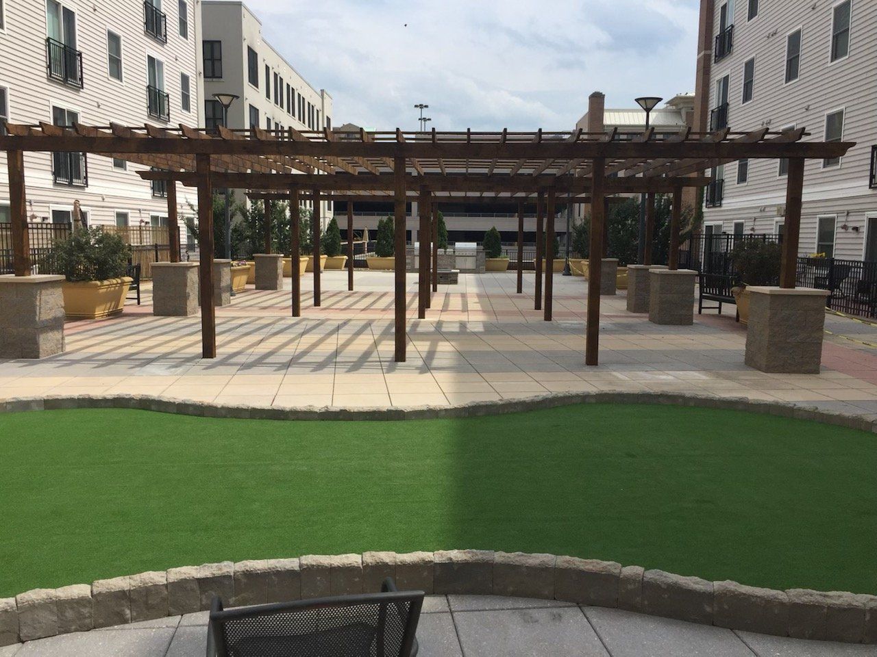 A courtyard with a pergola and a chair in the foreground
