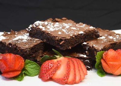 A white plate topped with brownies and strawberries.