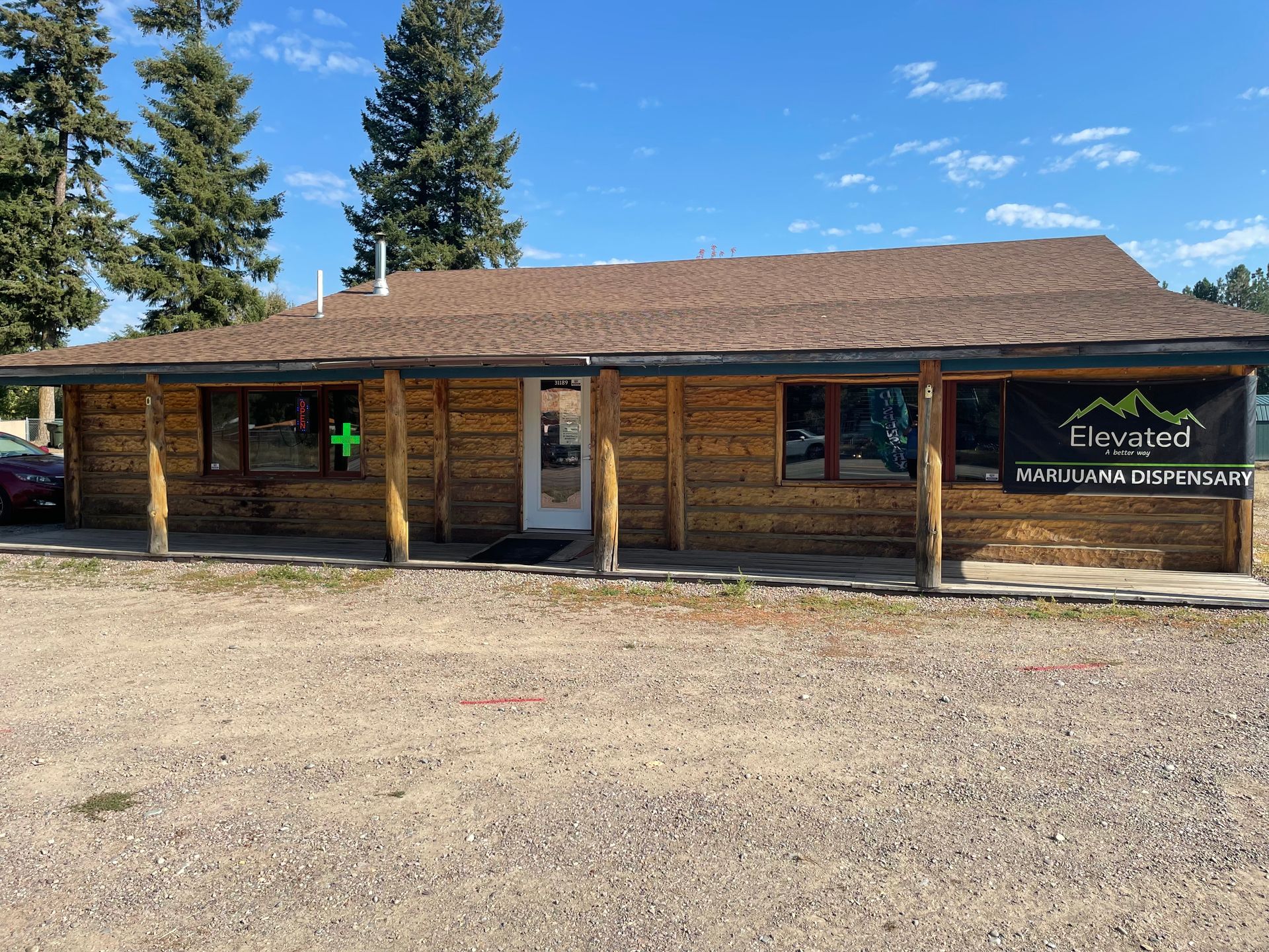 Black building with two green doors and a wooden ramp under a cloudy sky.