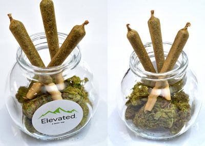 Four pre-rolled joints inside a glass jar with marijuana buds, labeled