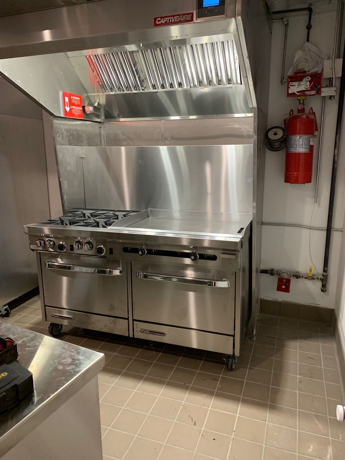 Stainless steel commercial kitchen stove with exhaust hood.