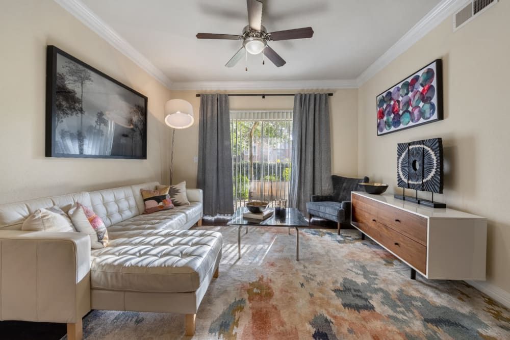 a living room with a couch, ottoman, coffee table, and ceiling fan at Marquis at Kingwood in Kingwood, TX.