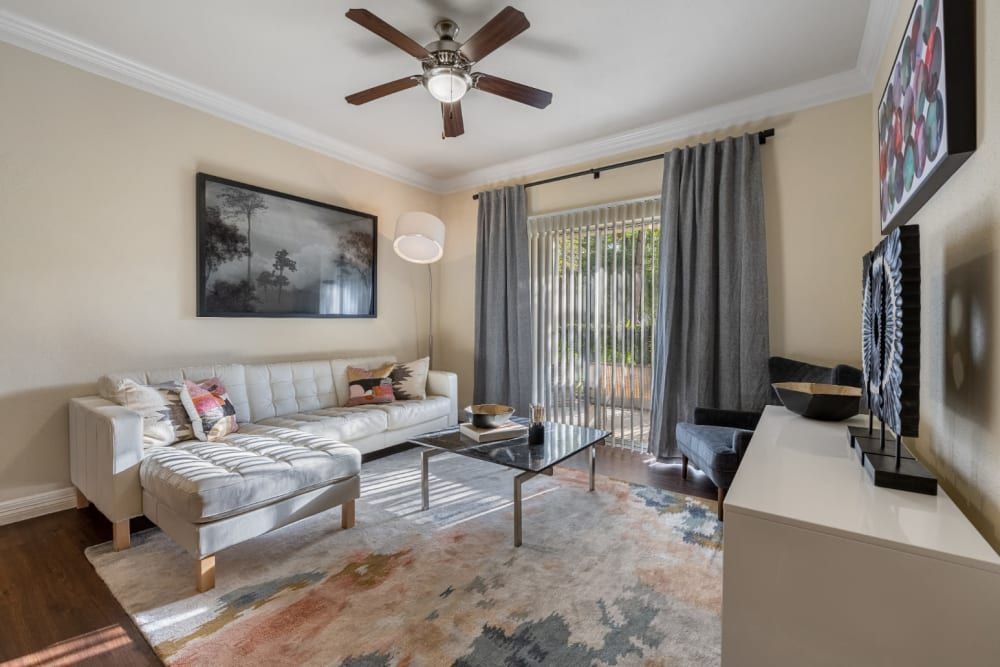 a living room with a couch, coffee table, television, and ceiling fan at Marquis at Kingwood in Kingwood, TX.