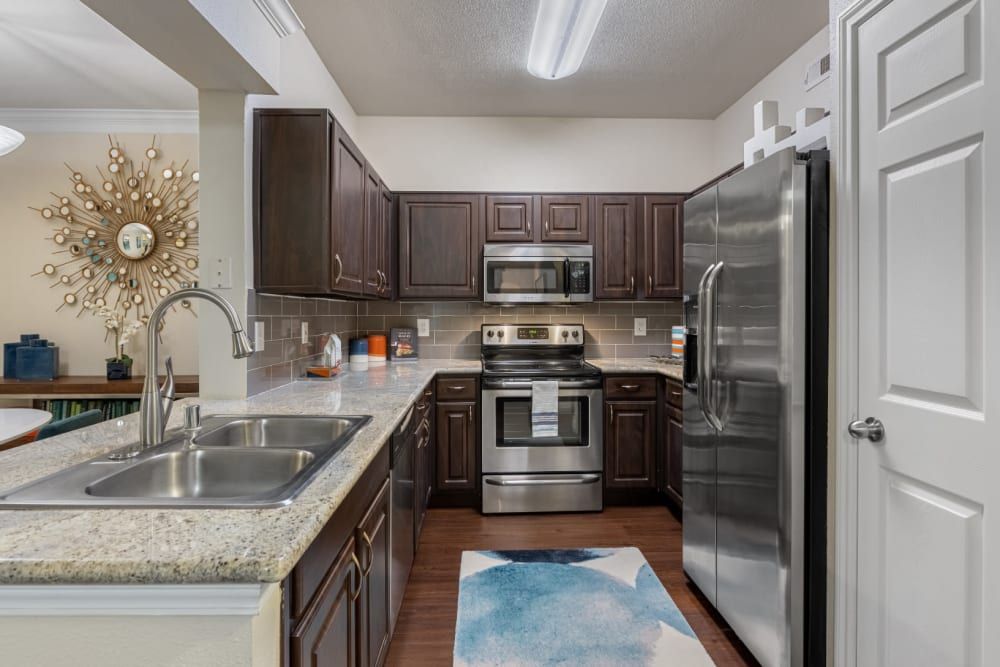 a kitchen with stainless steel appliances and granite counter tops at Marquis at Kingwood in Kingwood, TX.