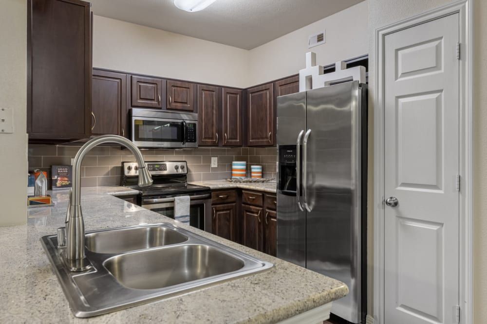 a kitchen with a sink, refrigerator, microwave, and stove at Marquis at Kingwood in Kingwood, TX.