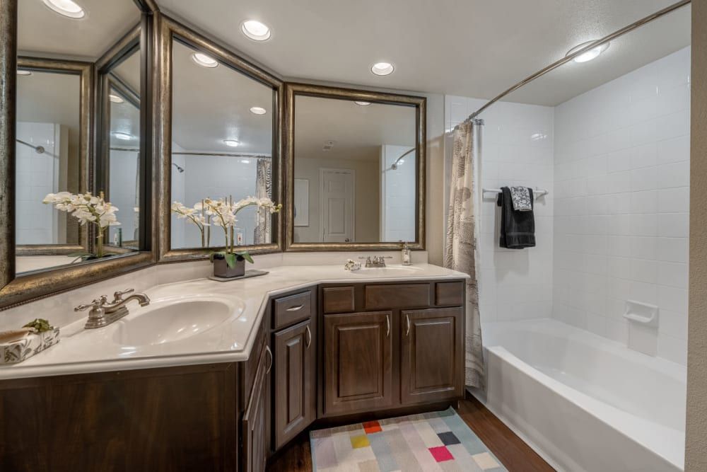 a bathroom with a sink, tub, and mirrors at Marquis at Kingwood in Kingwood, TX.