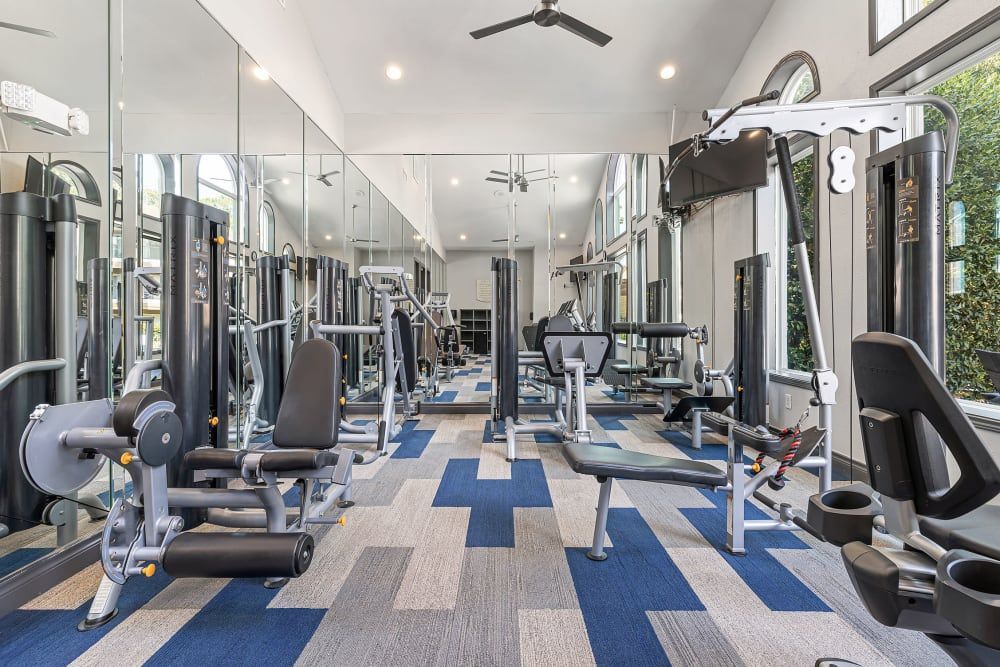 a large gym filled with lots of exercise equipment and mirrors at Marquis at Kingwood in Kingwood, TX.