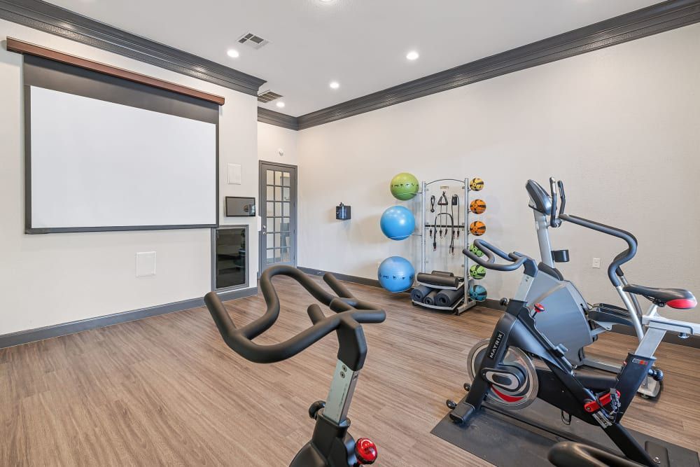a gym with a bicycle, treadmill, and projector screen at Marquis at Kingwood in Kingwood, TX.
