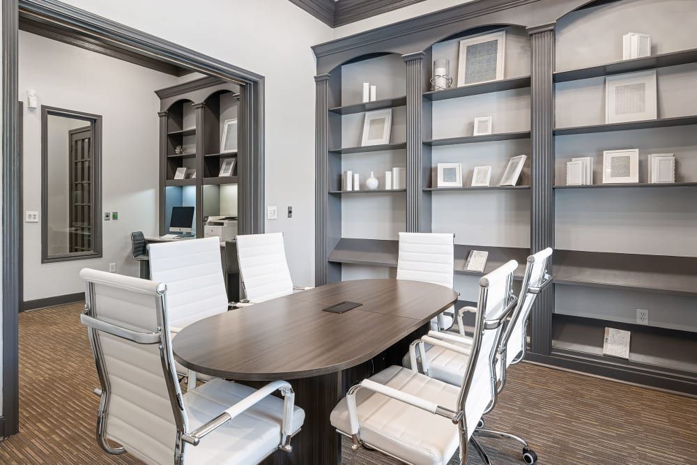 a conference room with a table and chairs and shelves at Marquis at Kingwood in Kingwood, TX.