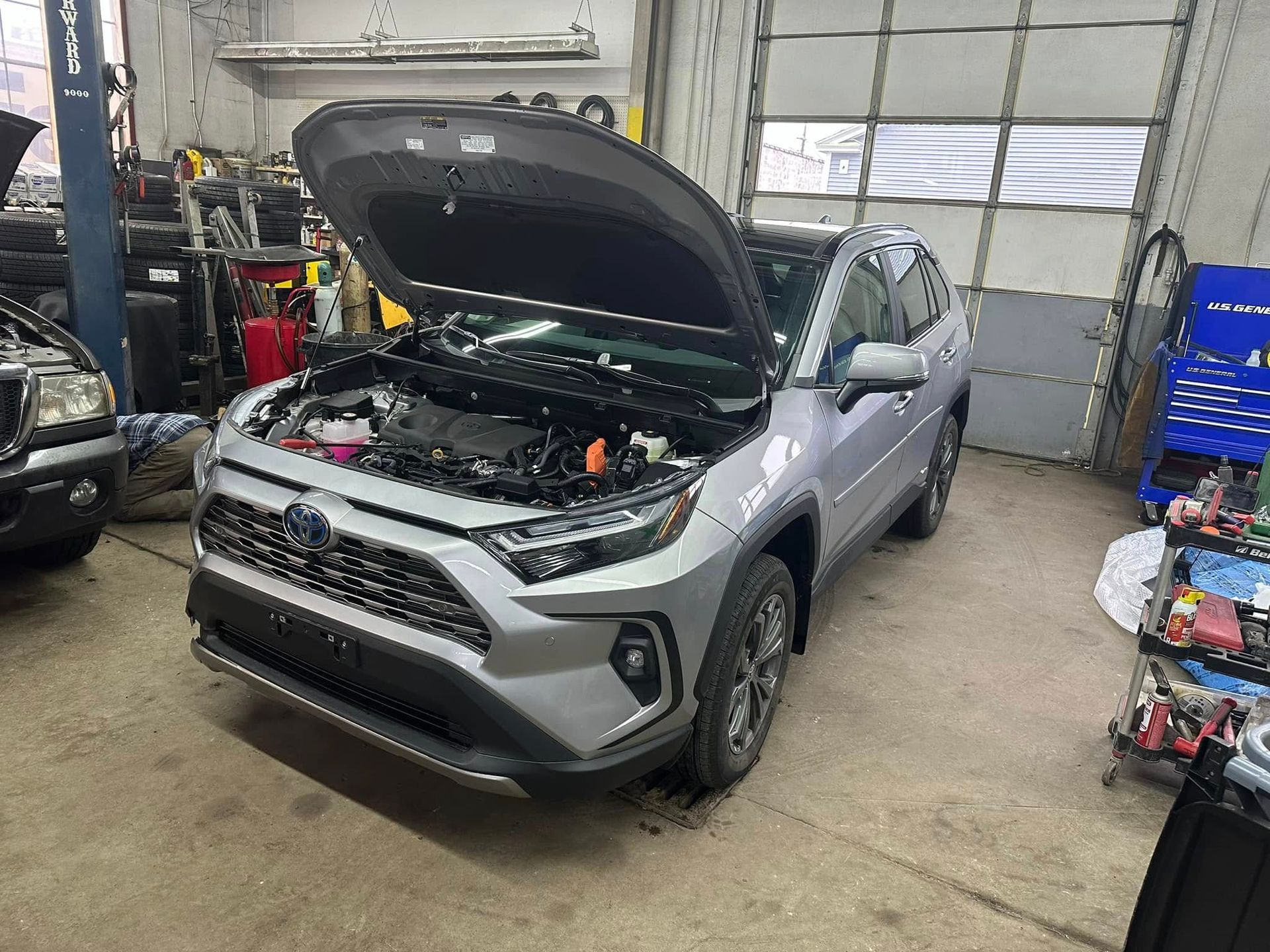 A toyota rav4 is sitting in a garage with its hood open.