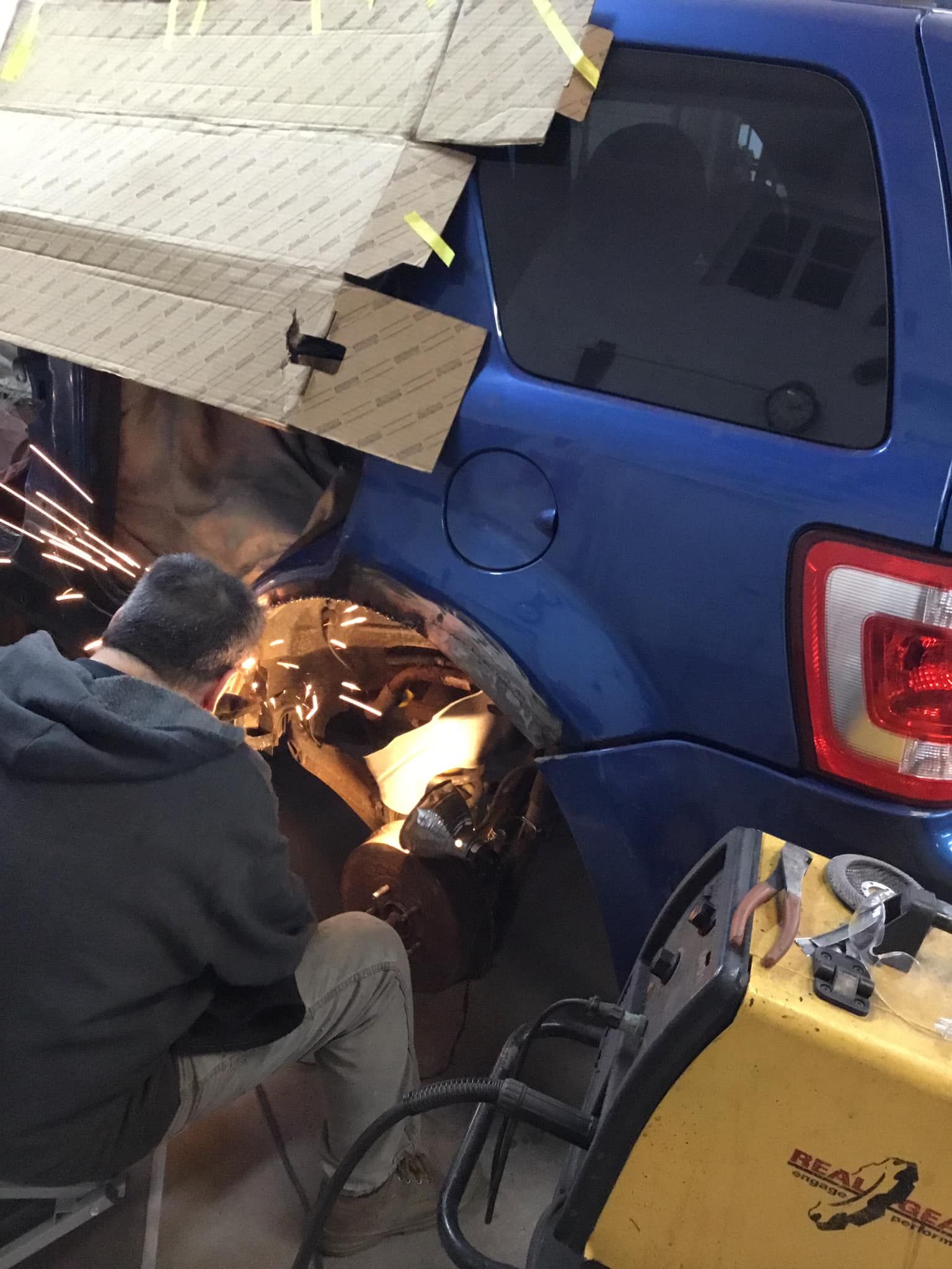 A man is working on a blue car in a garage