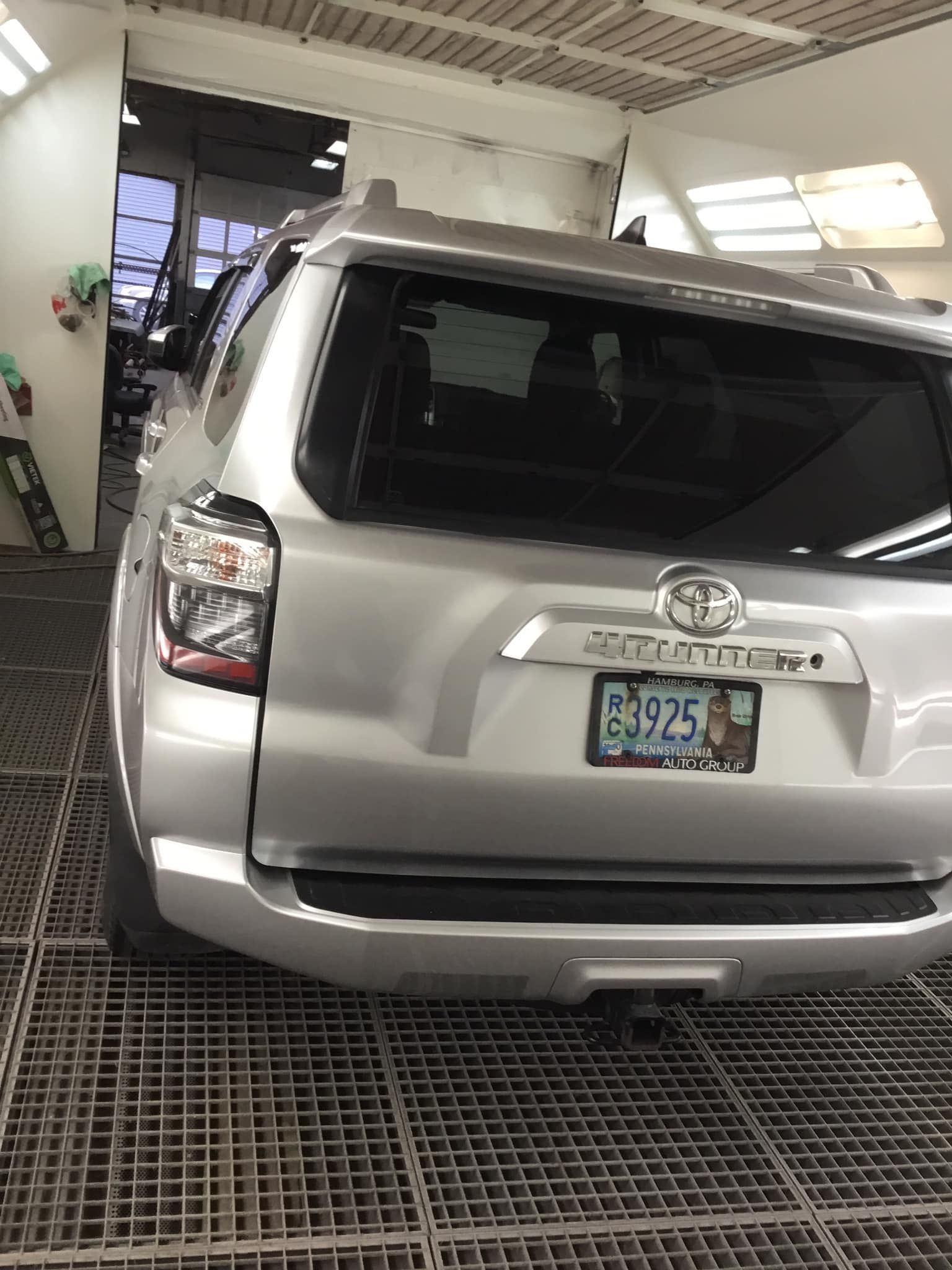 A silver toyota 4runner is parked in a garage.