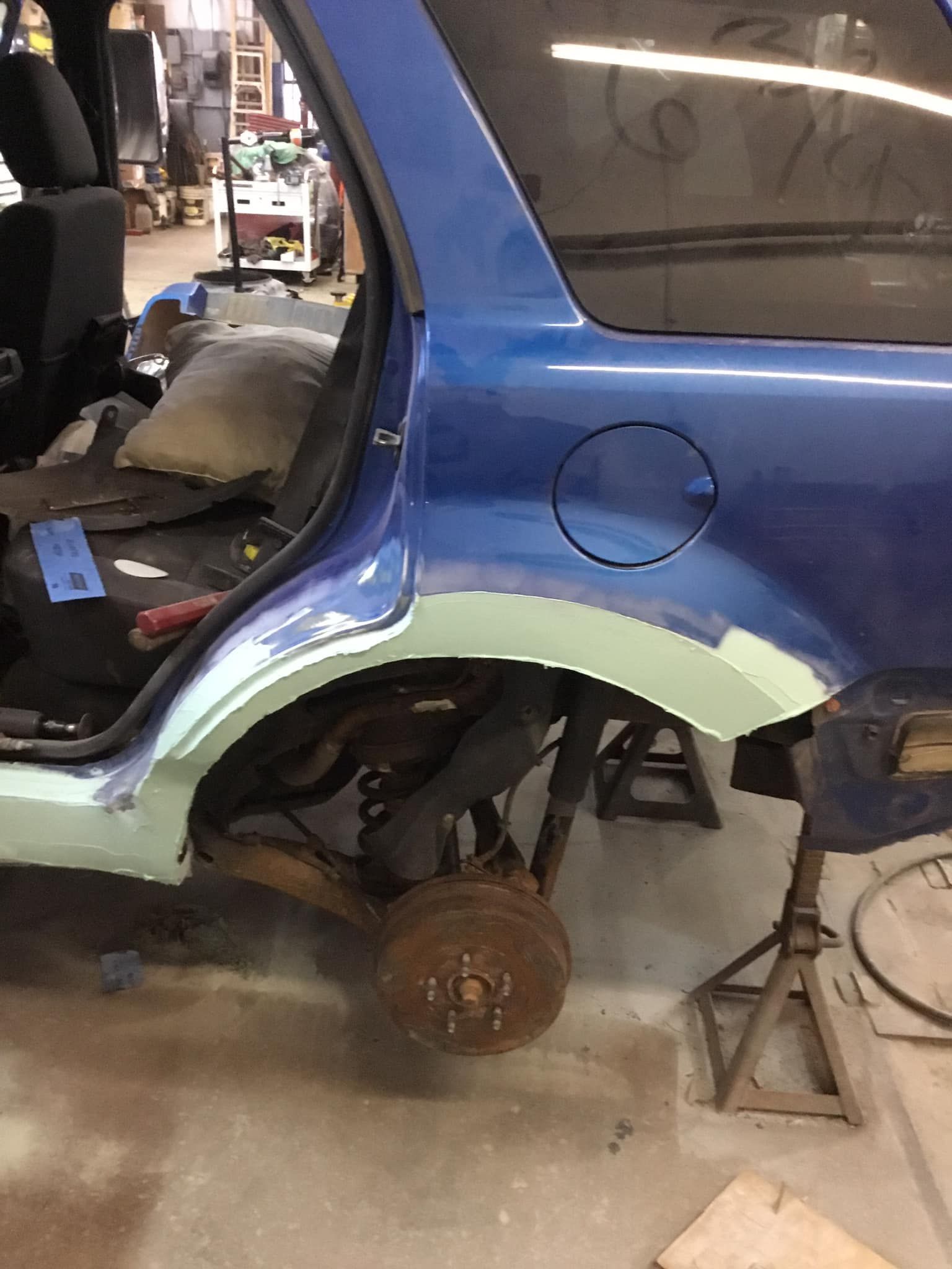 A blue car is being repaired in a garage.