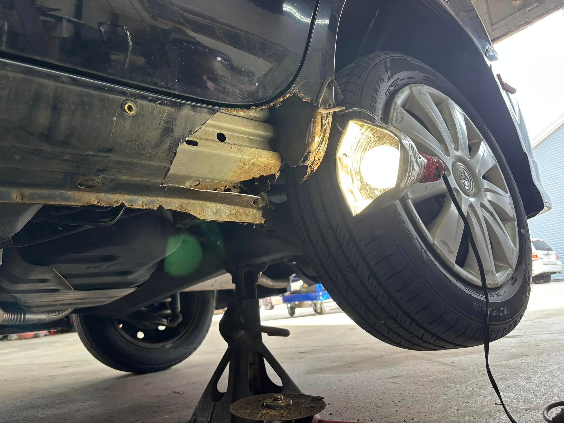 A car is sitting on a jack with a light attached to it.