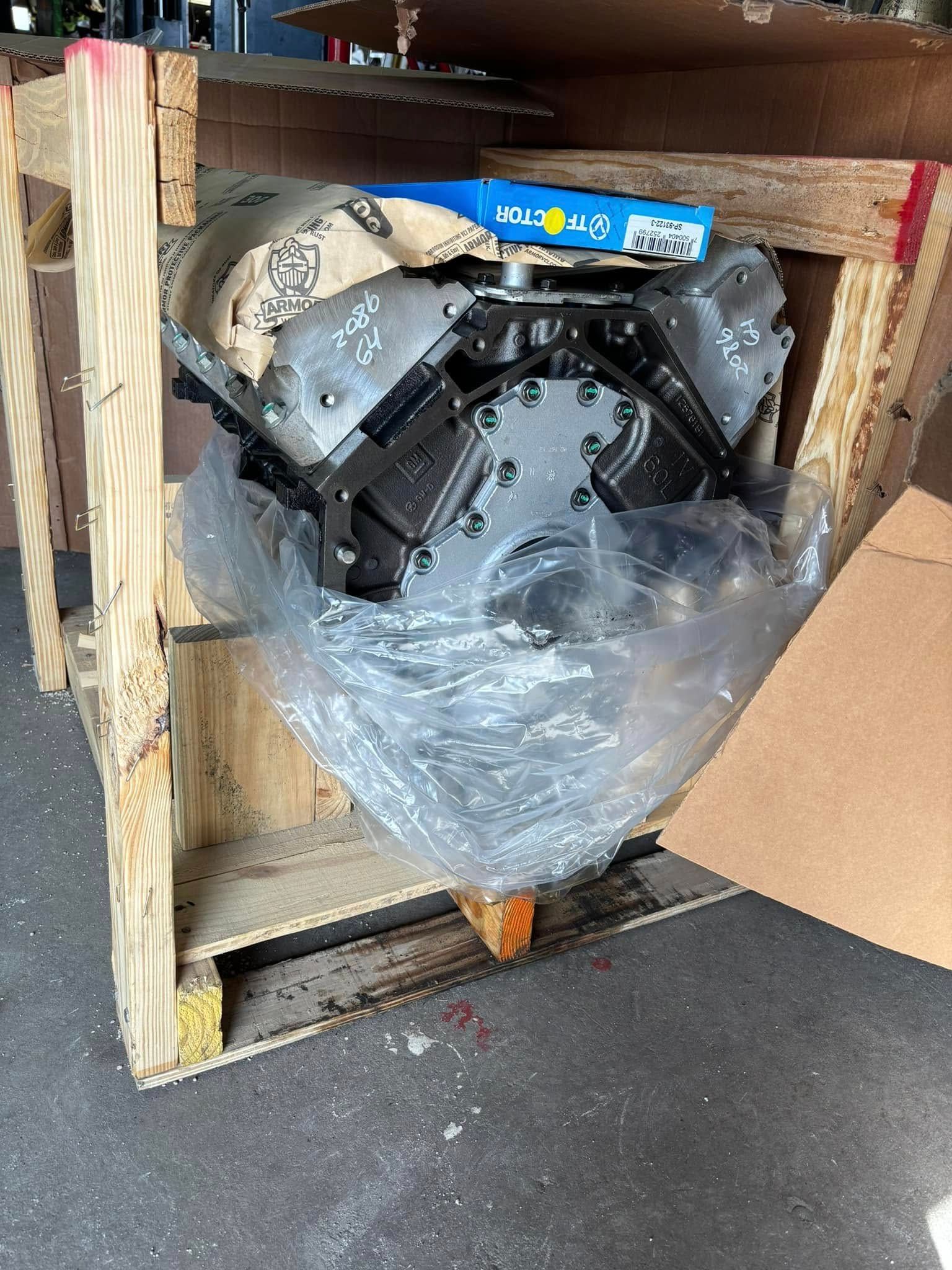 A motor is wrapped in plastic and sitting in a wooden crate.