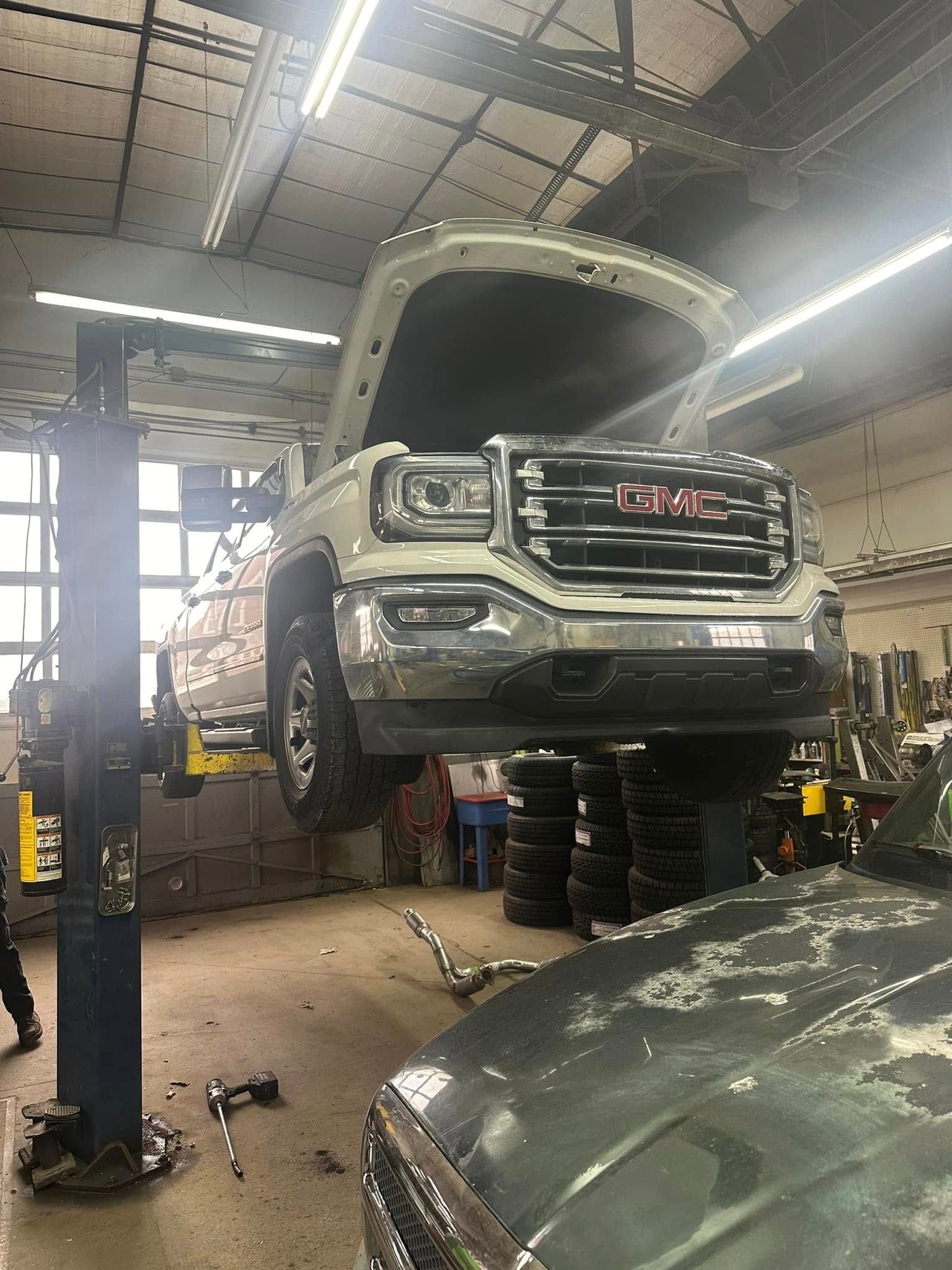 A gmc truck is sitting on a lift in a garage.