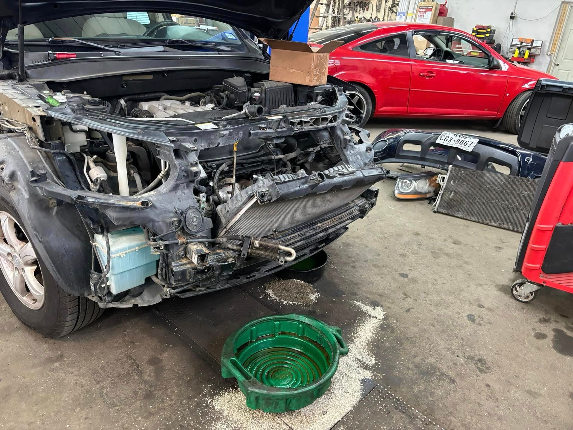 A car with the hood up is being worked on in a garage.