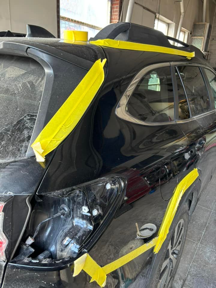 A black car with yellow tape on it is sitting in a garage.