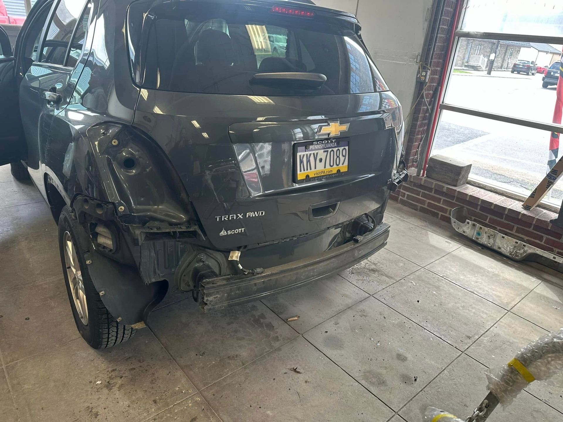 A car with a damaged back end is sitting in a garage.