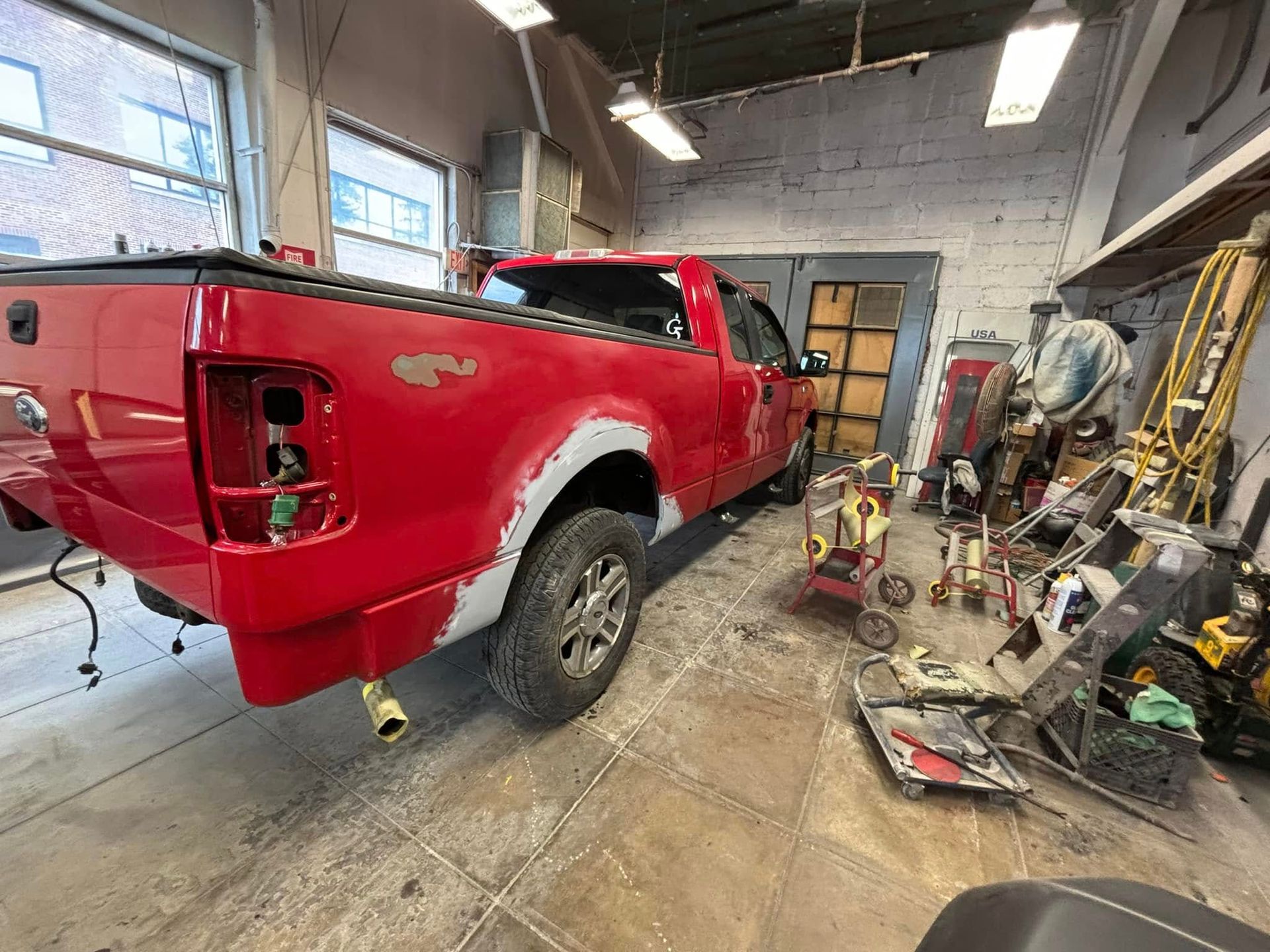 A red truck is being painted in a garage.