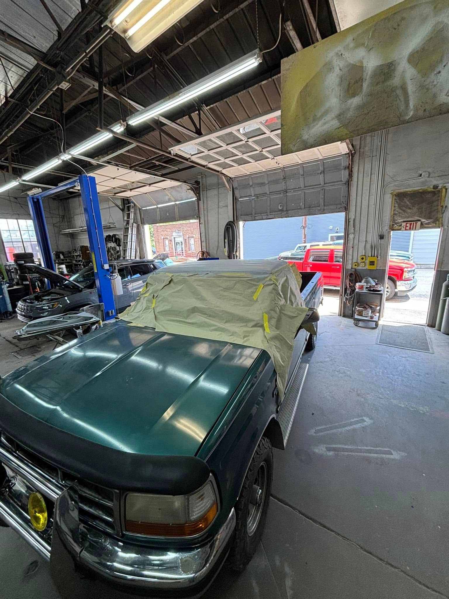A green truck is sitting in a garage covered in paint.