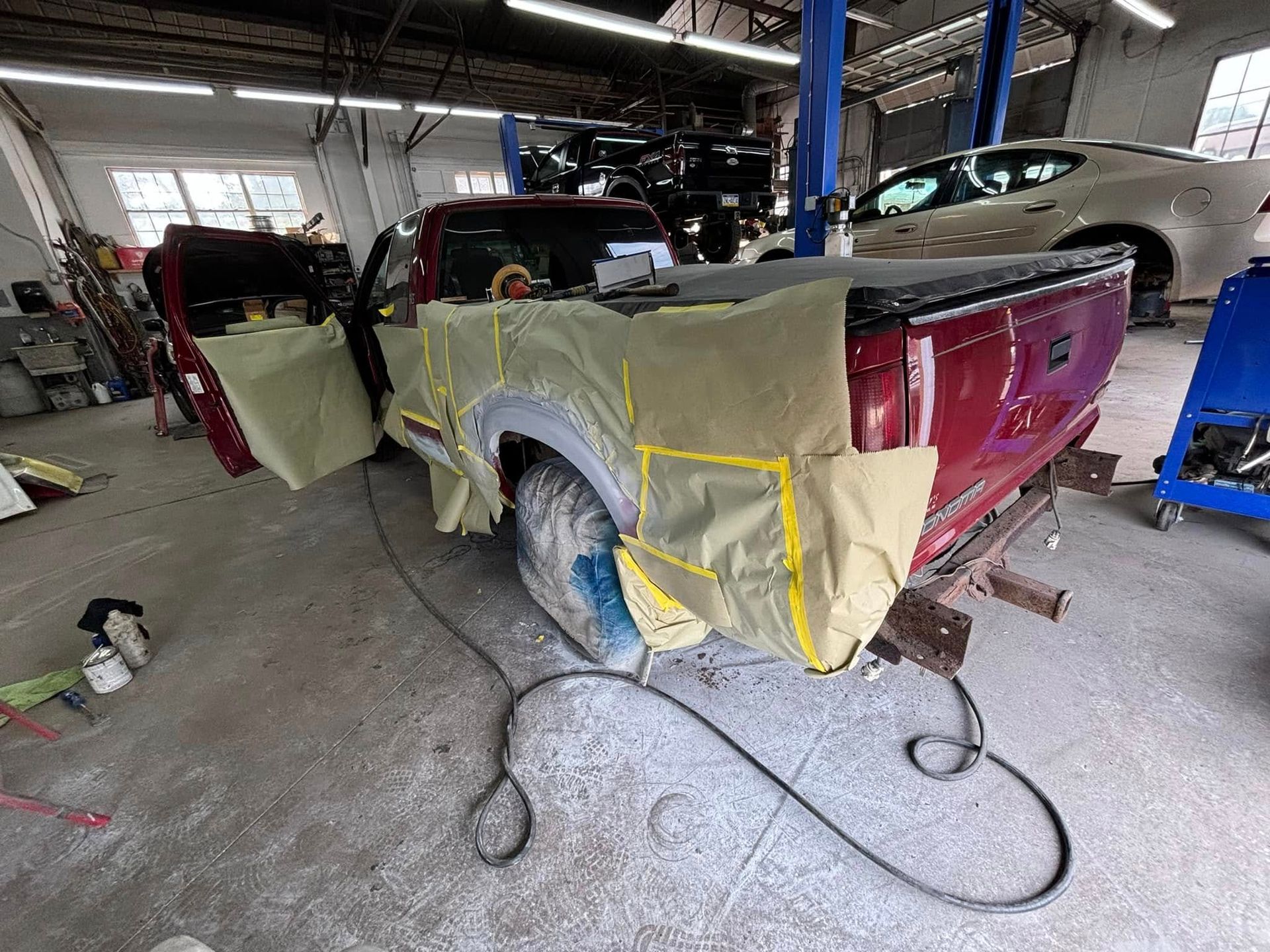 A red truck is being painted in a garage.