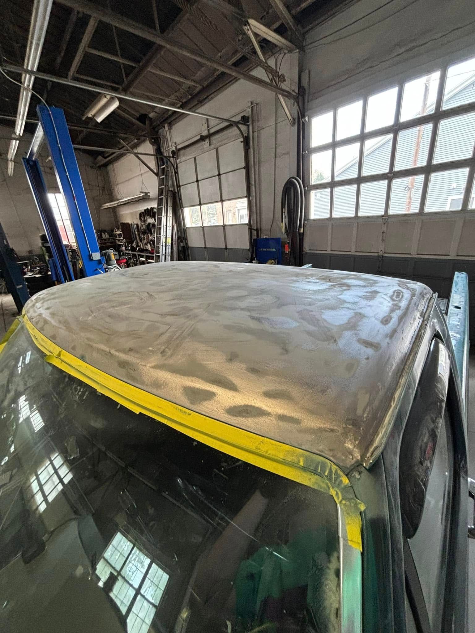The roof of a car is being painted in a garage.