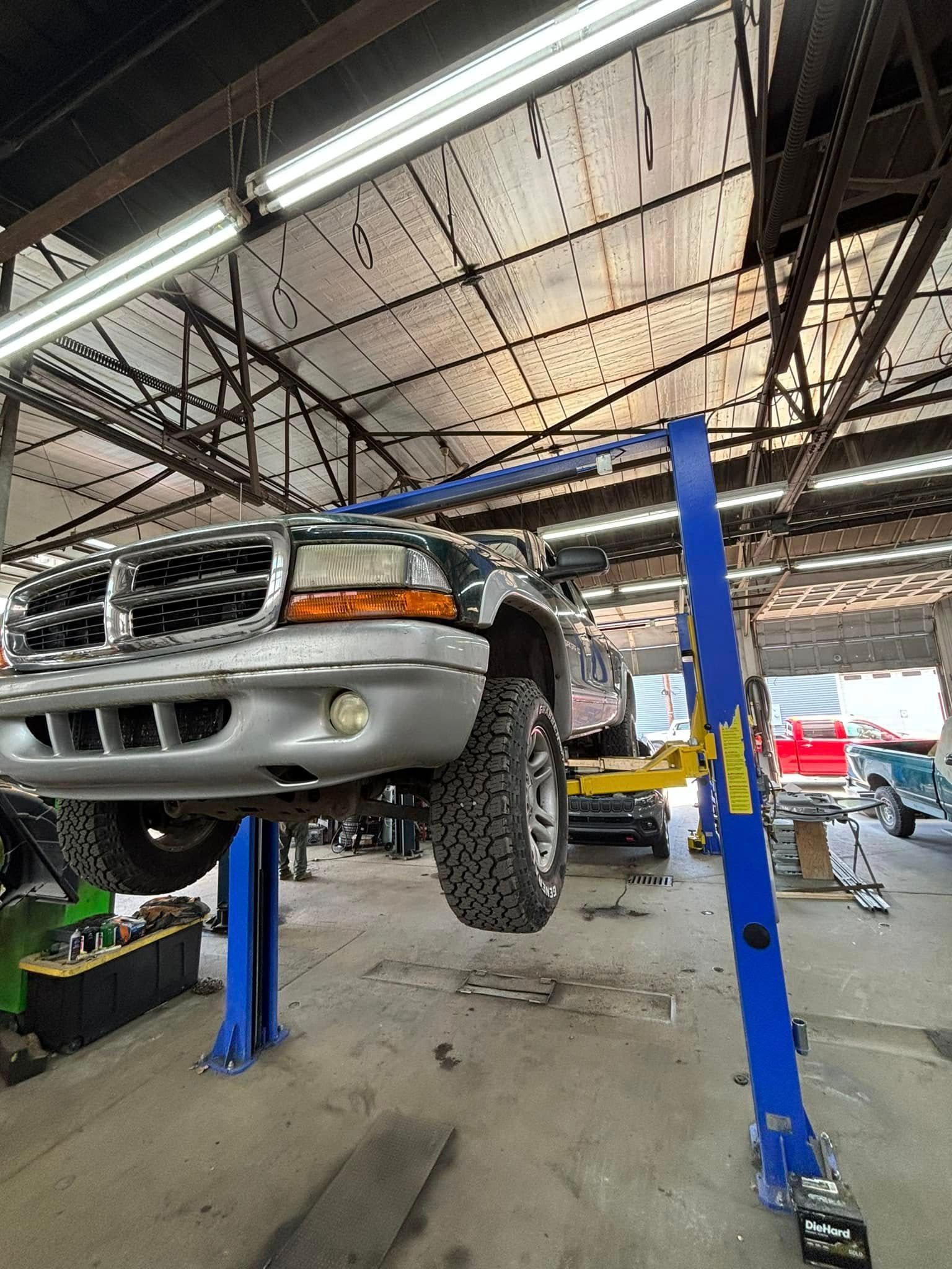 A truck is sitting on a lift in a garage.