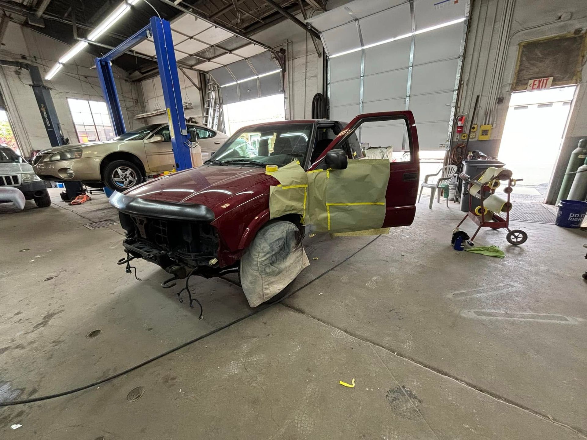 A red truck is being painted in a garage.