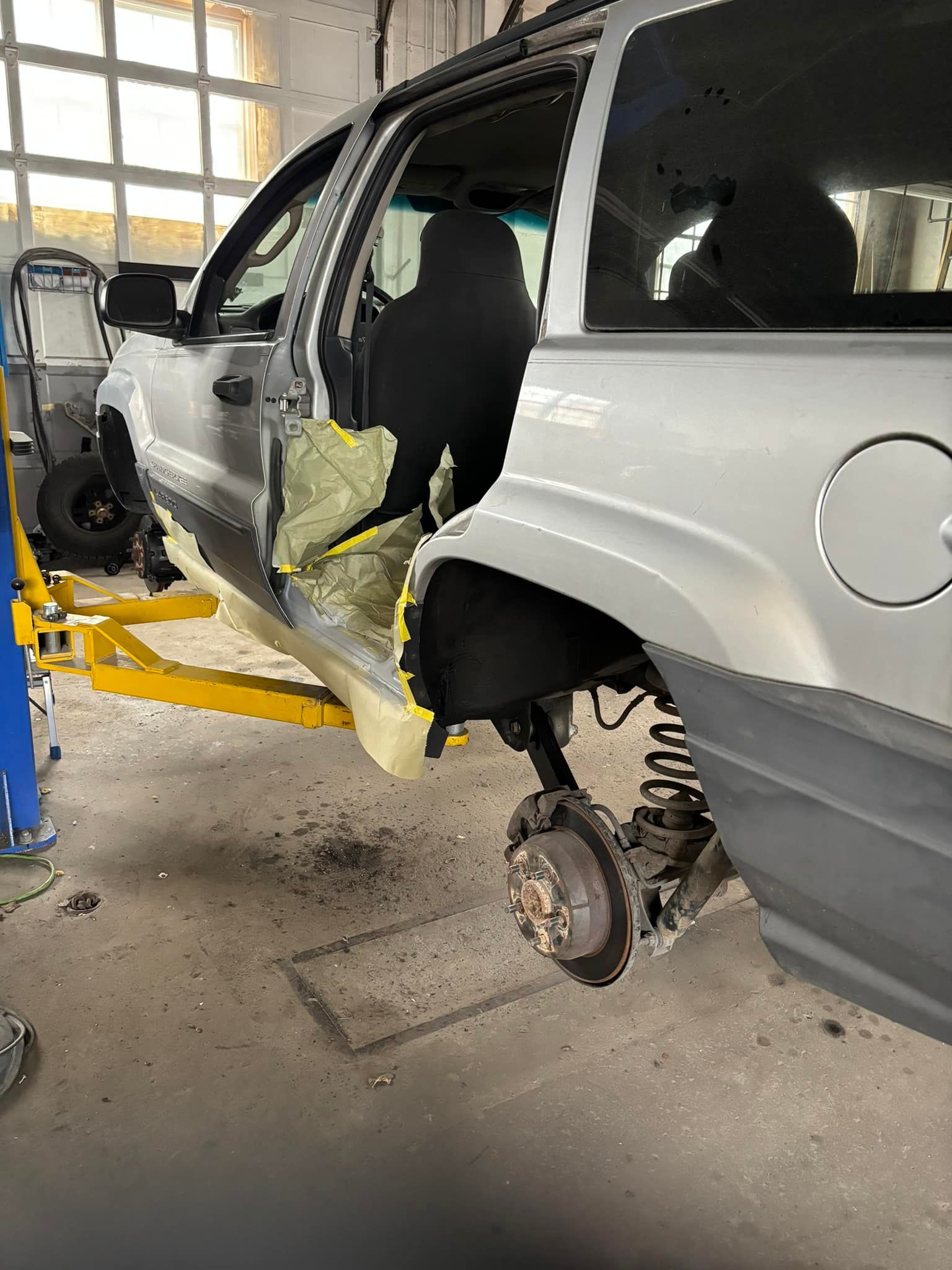 A silver suv is sitting on a lift in a garage.