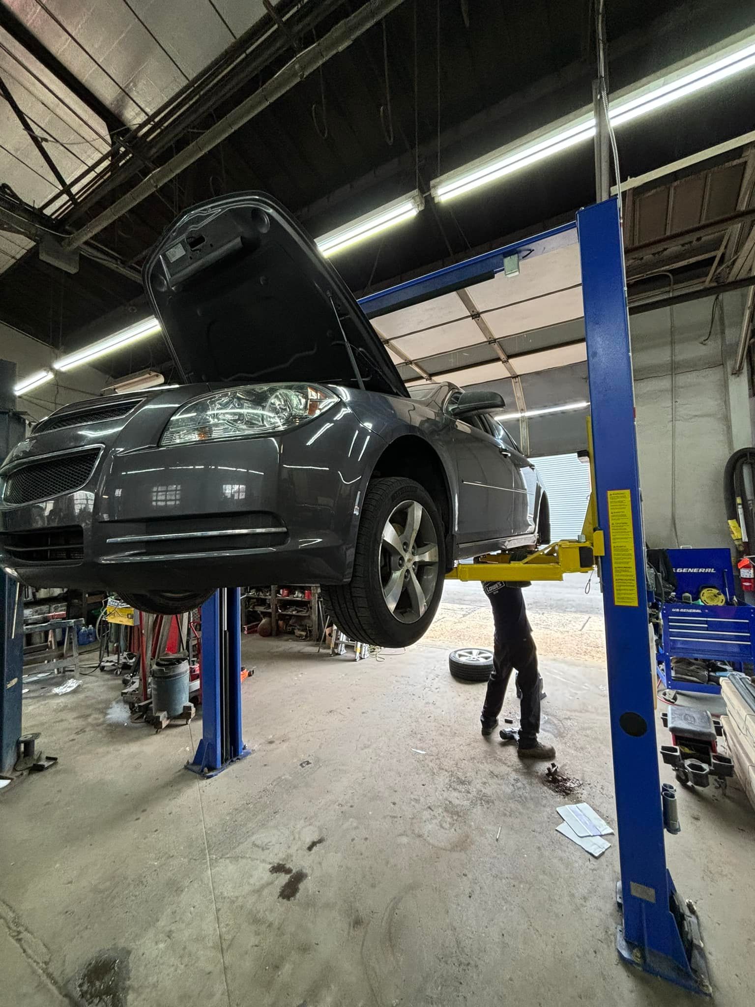 A car is sitting on a lift in a garage with the hood up.
