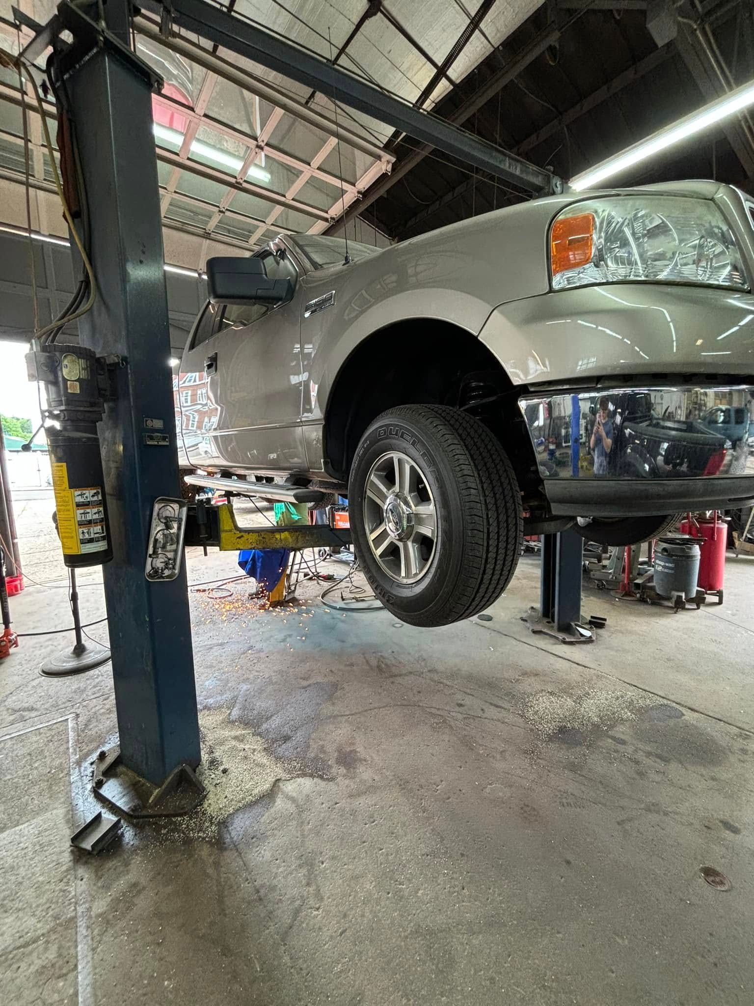 A truck is sitting on a lift in a garage.