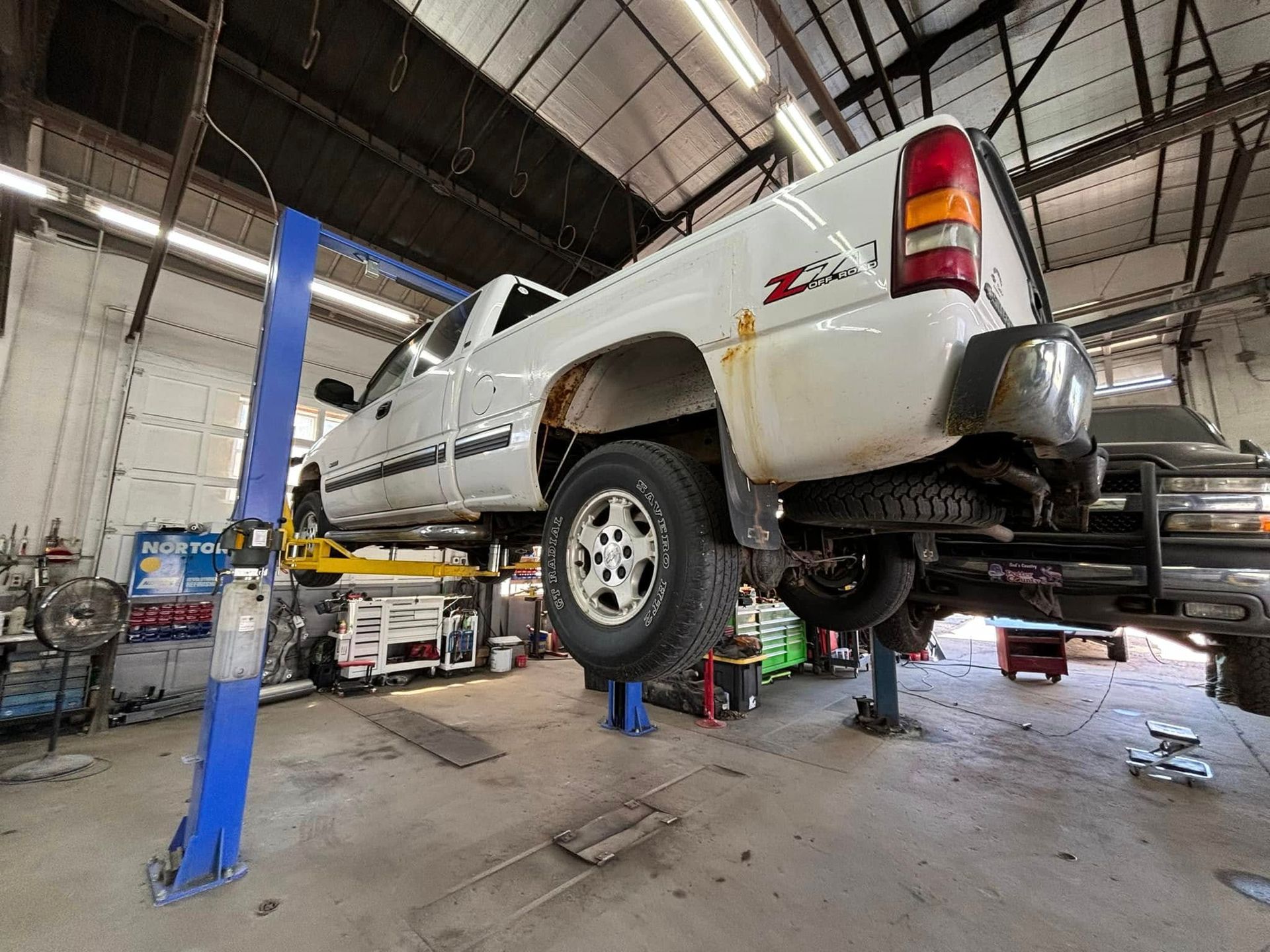 A white truck is sitting on a lift in a garage.