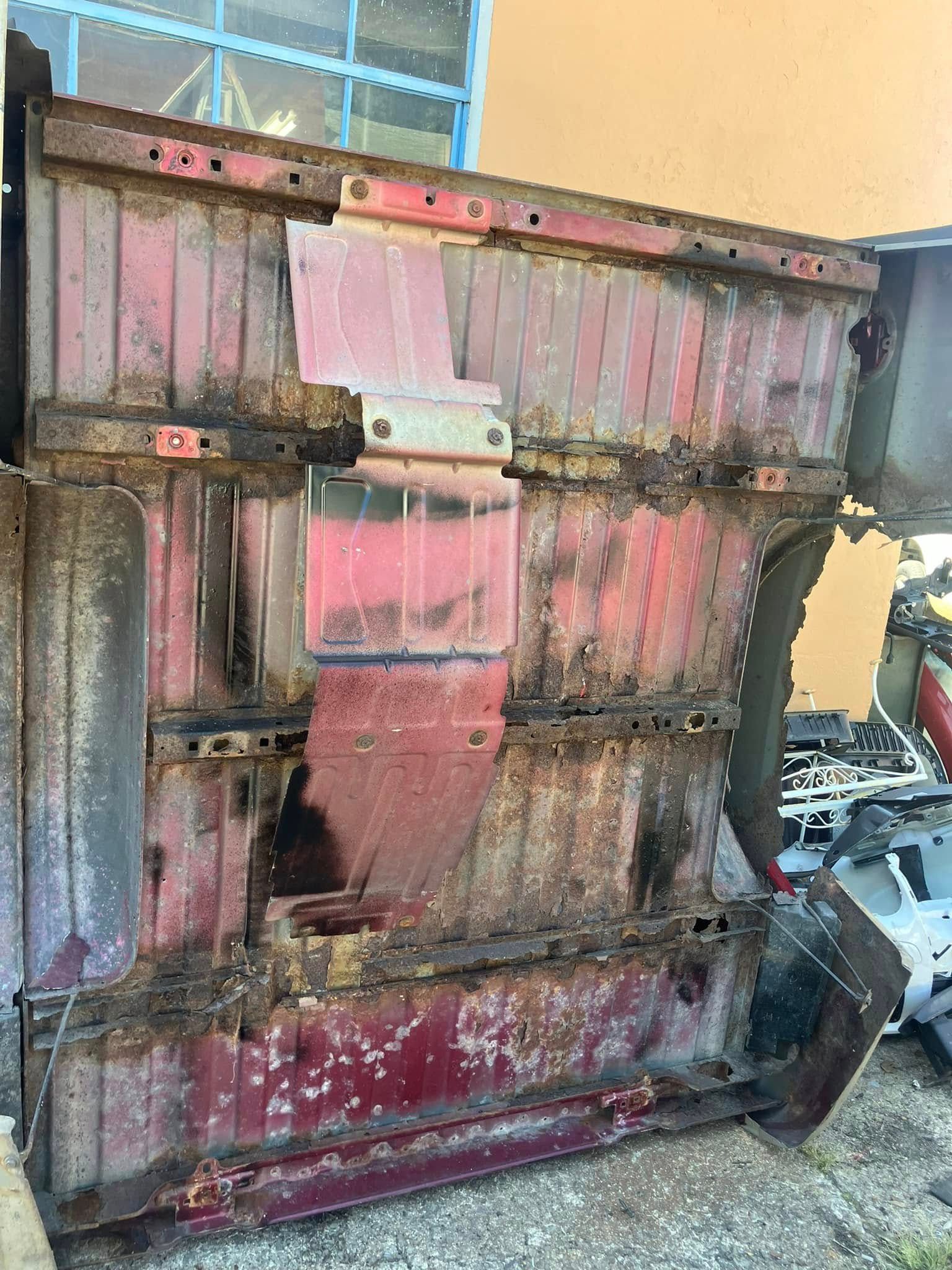 A piece of rusty metal is sitting on the ground in front of a building.