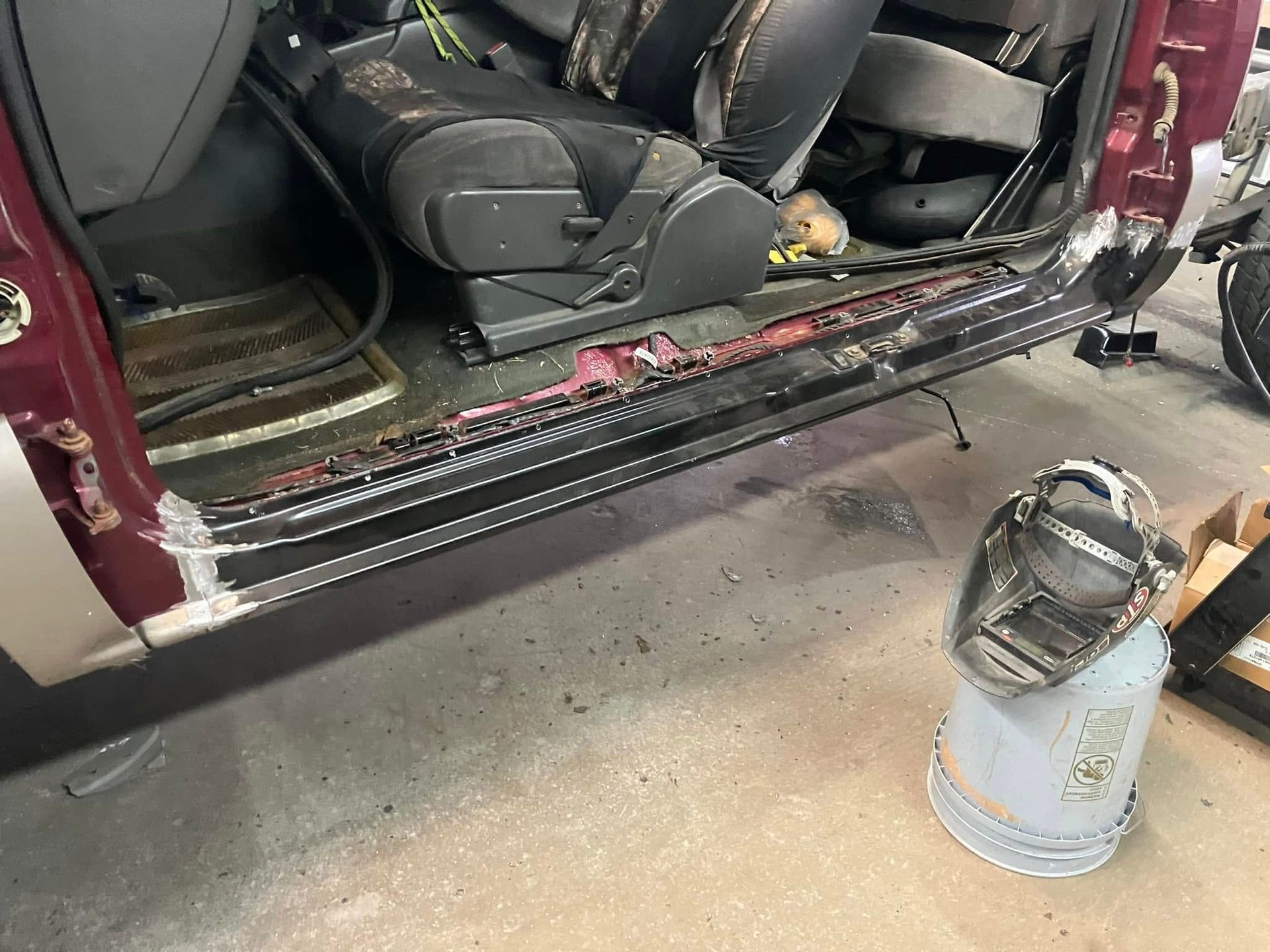 The side of a car is being repaired in a garage.