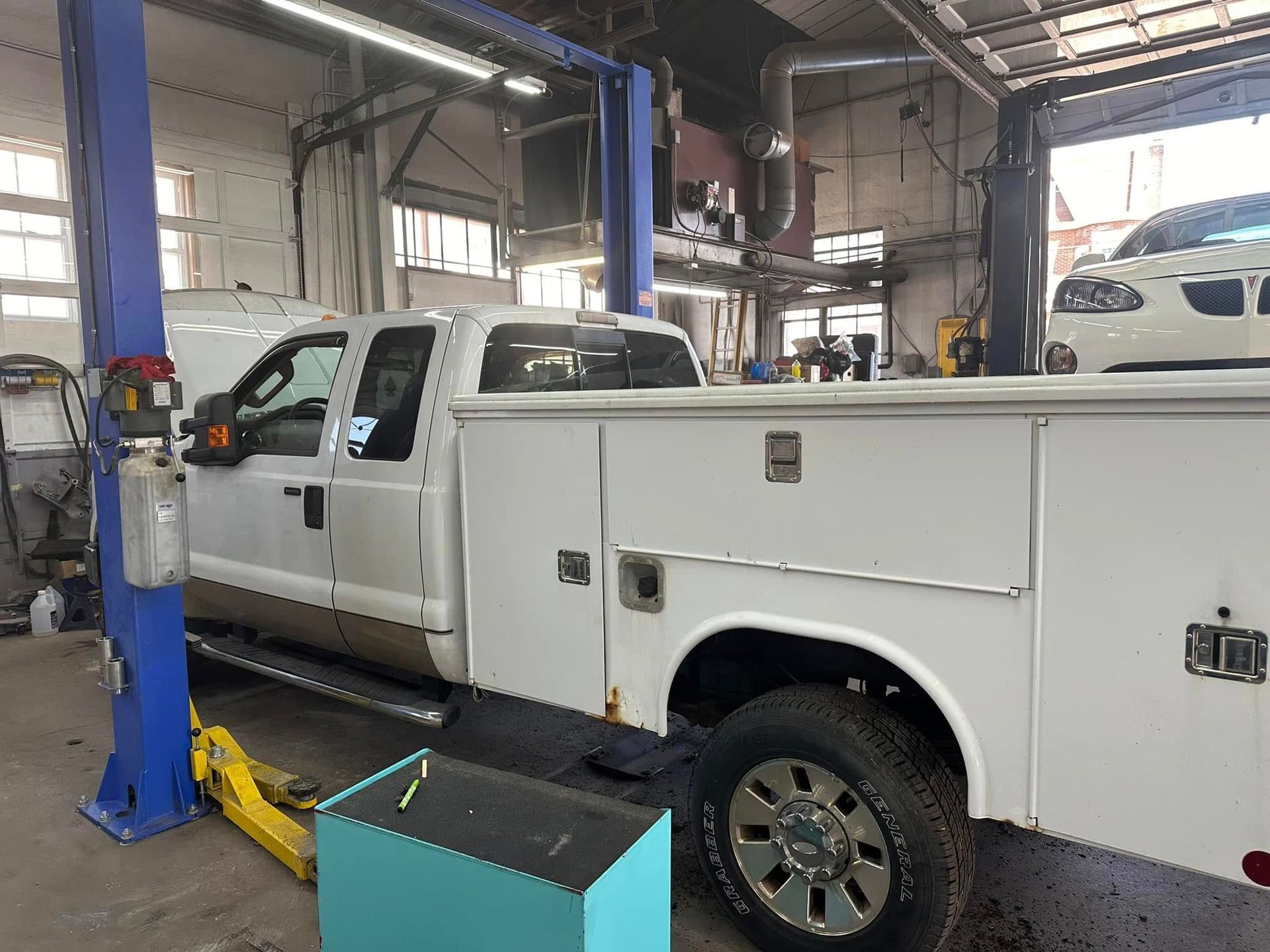A white truck is parked on a lift in a garage.