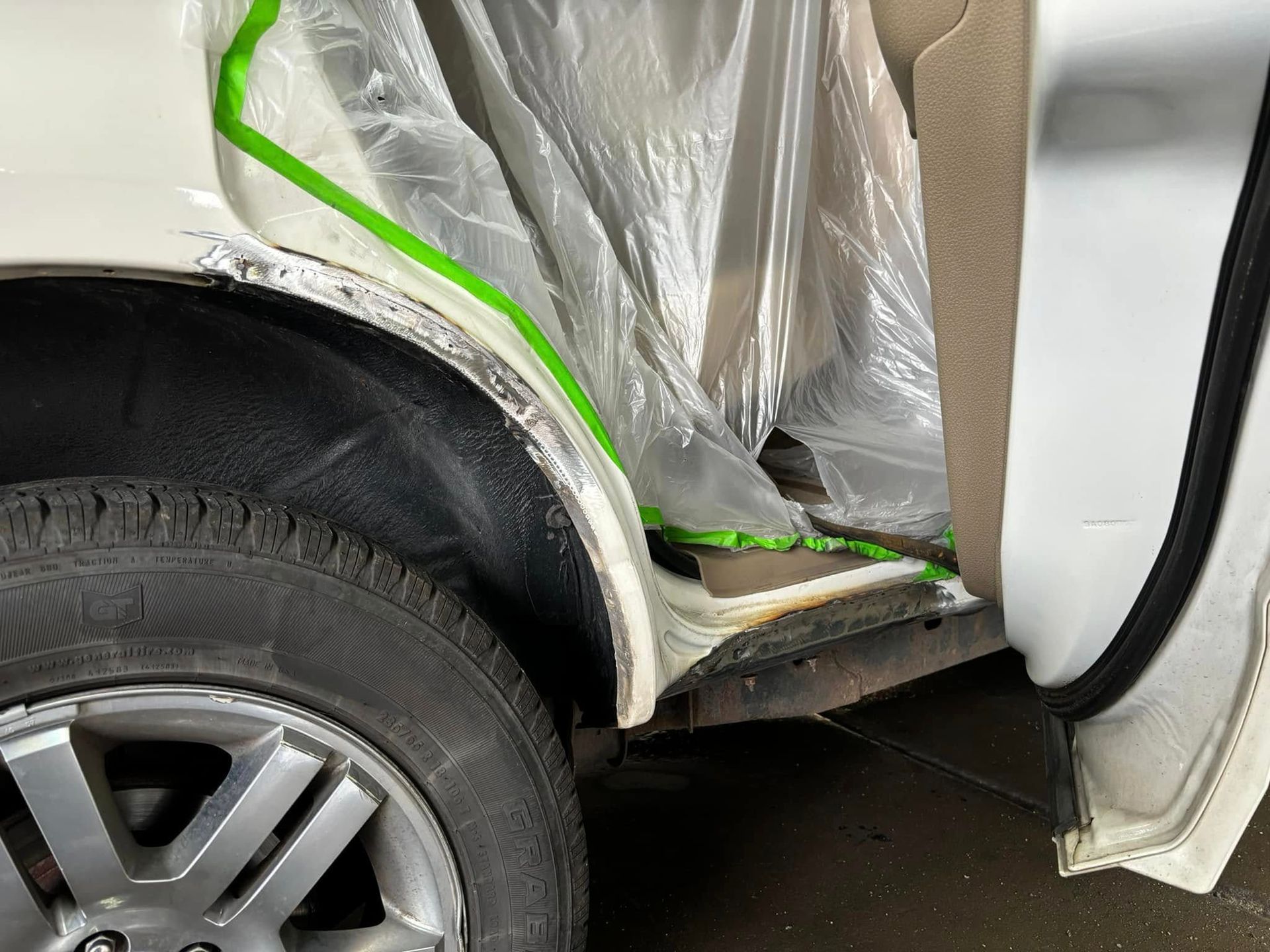 The fender of a white car is covered in plastic.