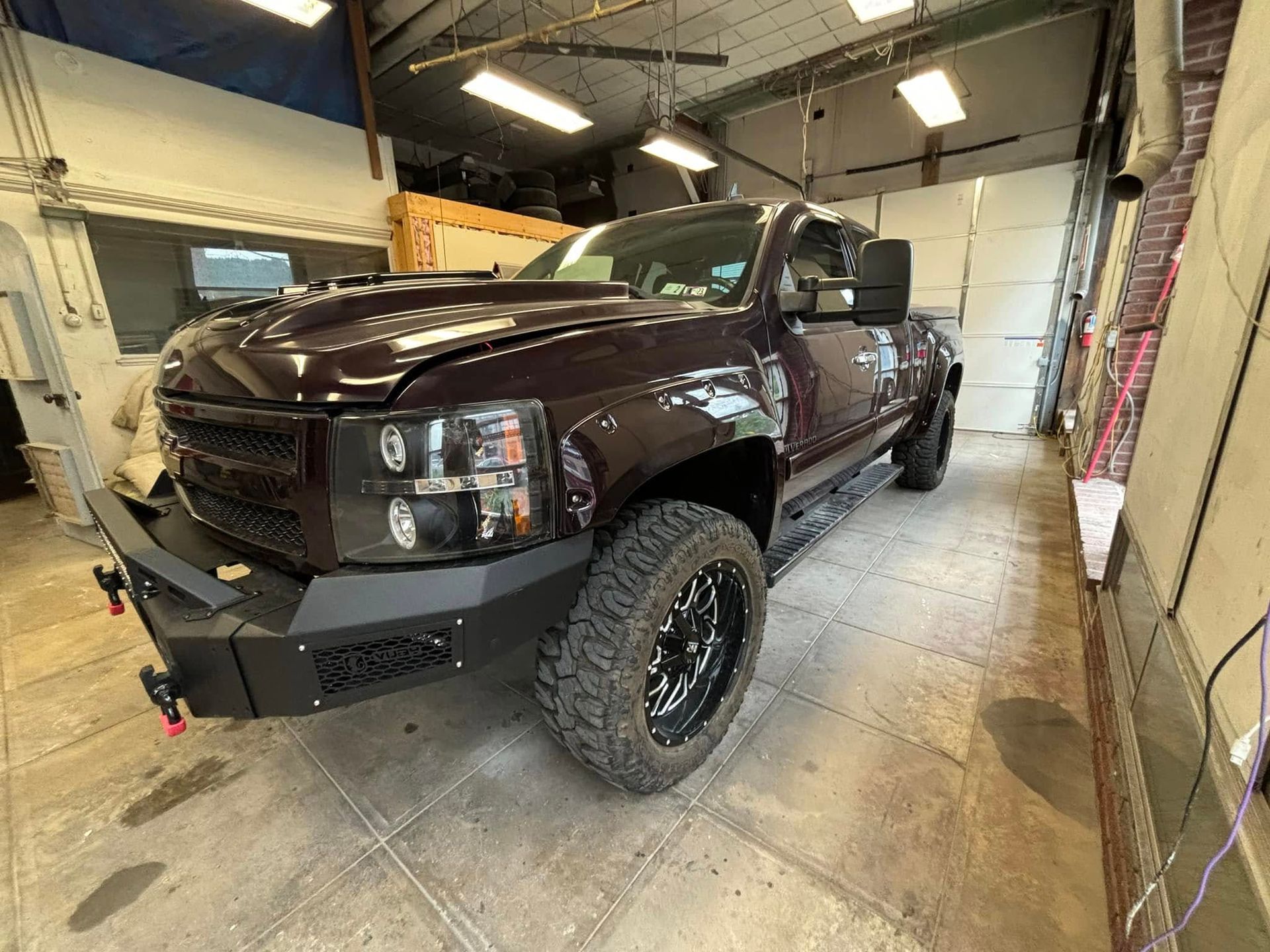 Dark red pickup truck parked inside a garage. Black custom front bumper, wheels, and tinted
headligh